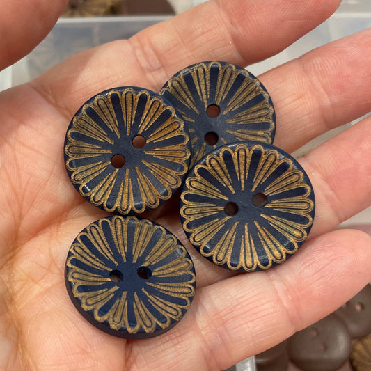 Hand holding three decorative buttons with a clear container of buttons in the background