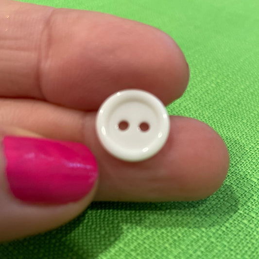 White button held between fingers against a green background