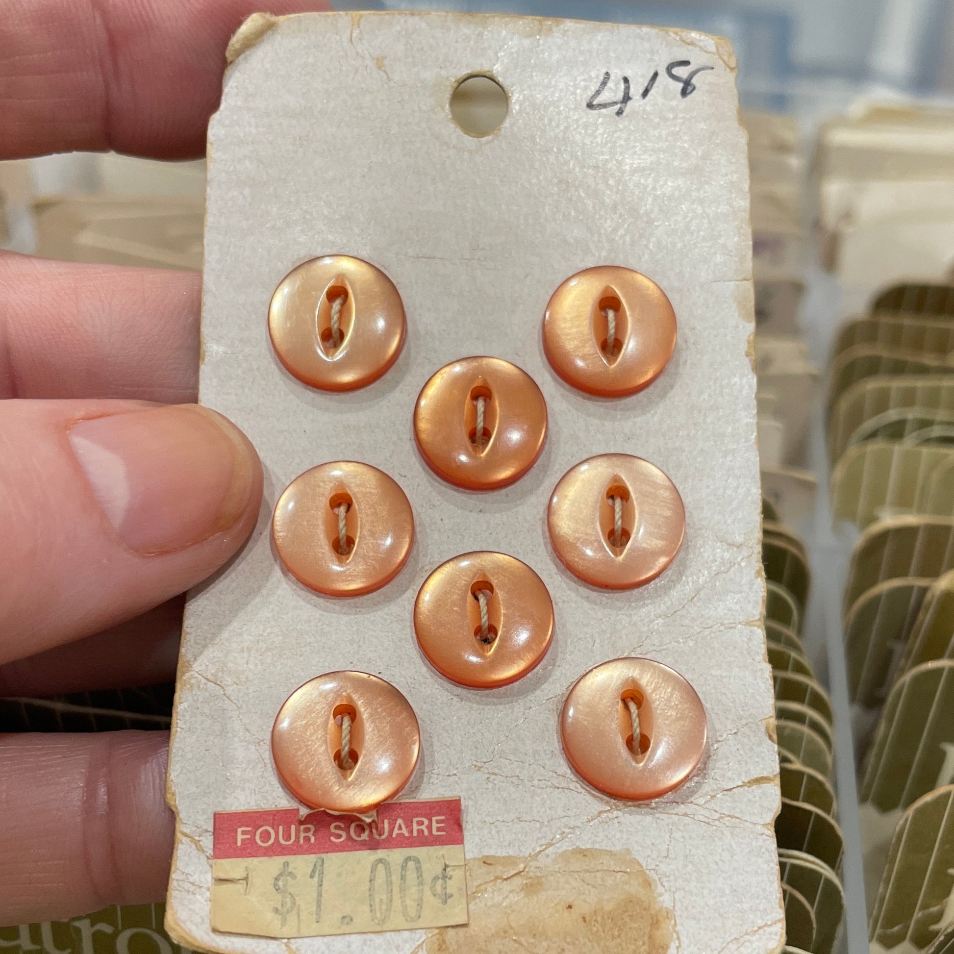 Set of gold buttons on a card held by a hand with a blurred background