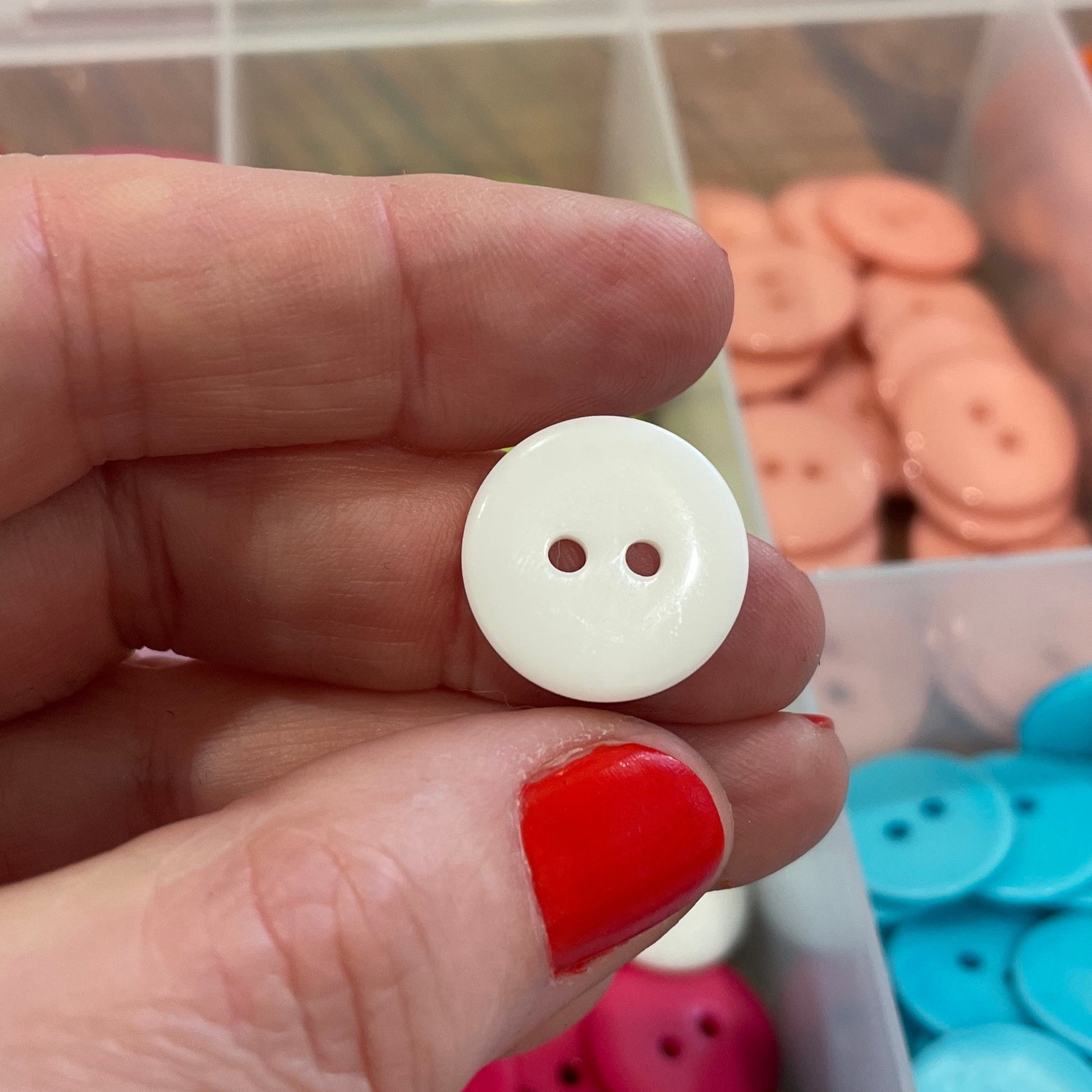 Hand holding a white button with colorful buttons in the background