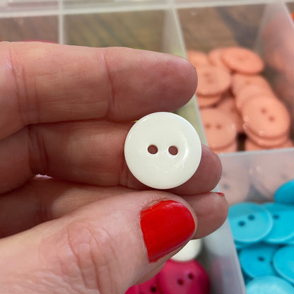 Hand holding a white button with colorful buttons in the background