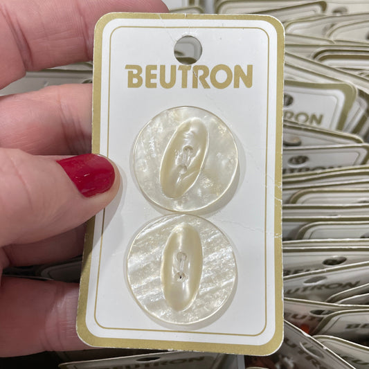 Hand holding a pair of buttons on a BEUTRON card with a blurred background
