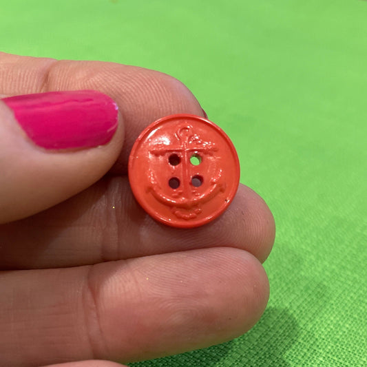 Hand holding a small orange button against a green background