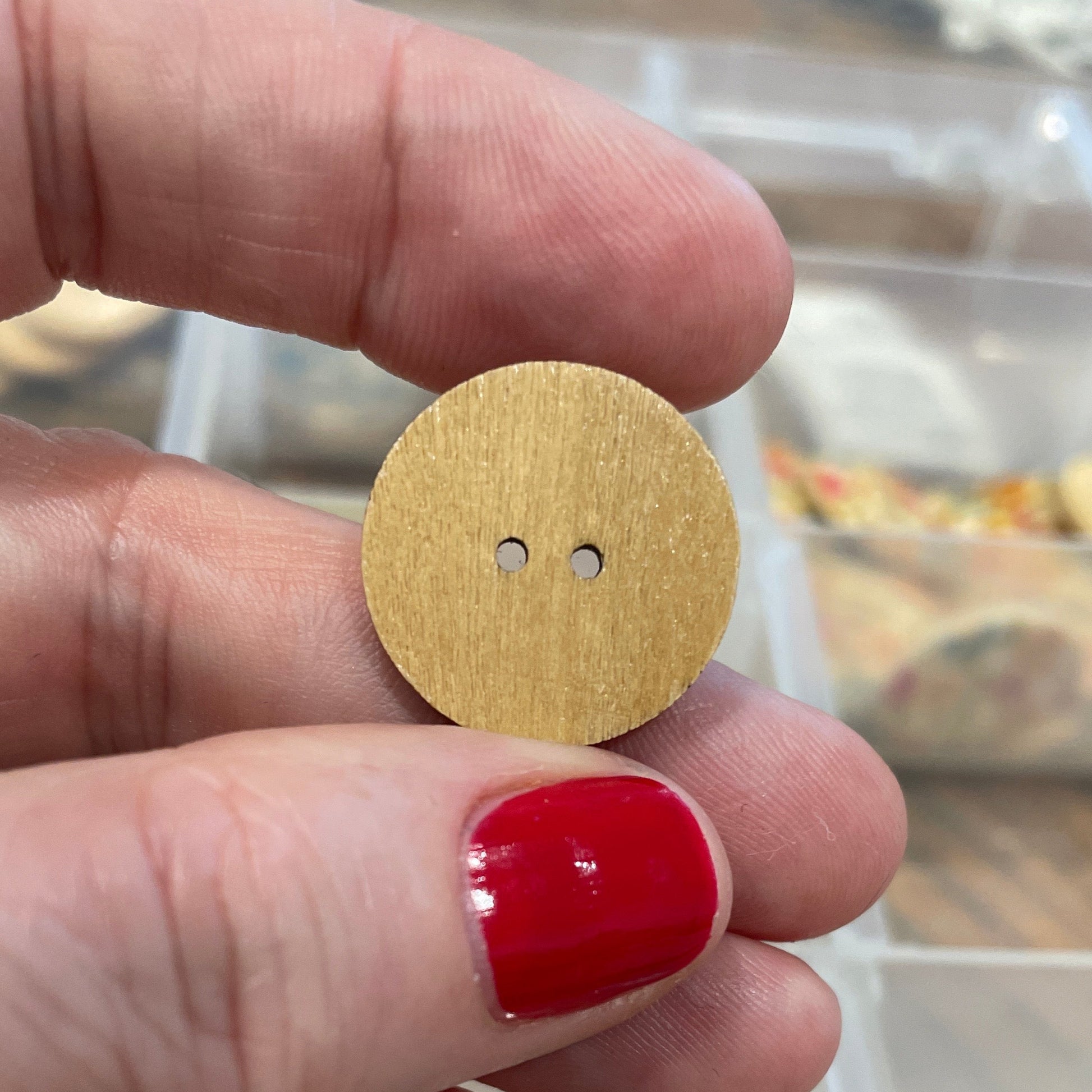 Gold button held between fingers with a blurred background