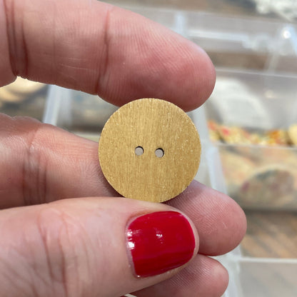 Gold button held between fingers with a blurred background