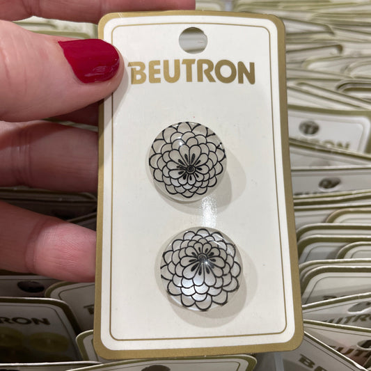 Pair of buttons on a BEUTRON card held by a hand with red nail polish.