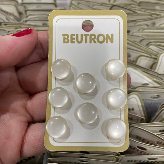 Beutron buttons displayed on a card held by a hand with red nail polish.
