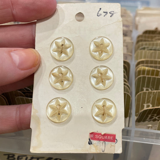 Gold star-shaped buttons on a card held by a hand with a blurred background