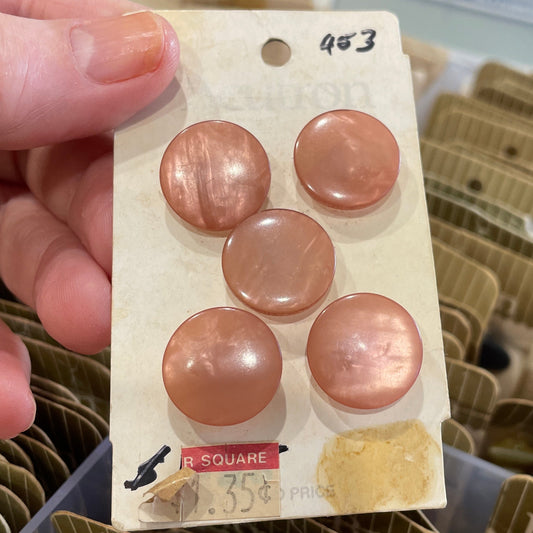 Card with pink buttons held by a hand, with a blurred background of similar cards.
