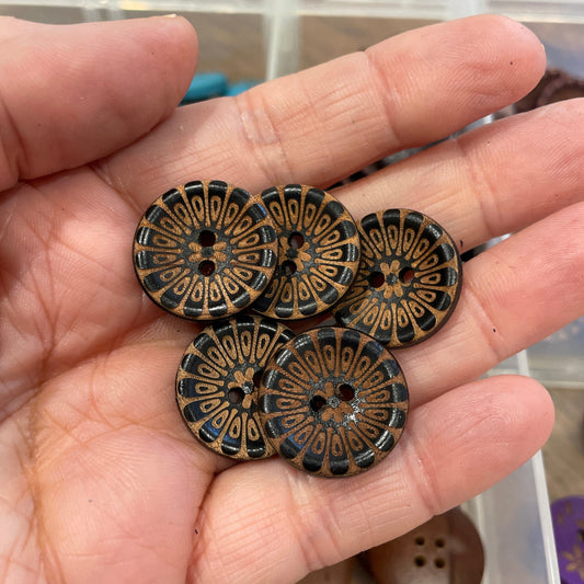 Hand holding decorative buttons with a blurred background of more buttons.