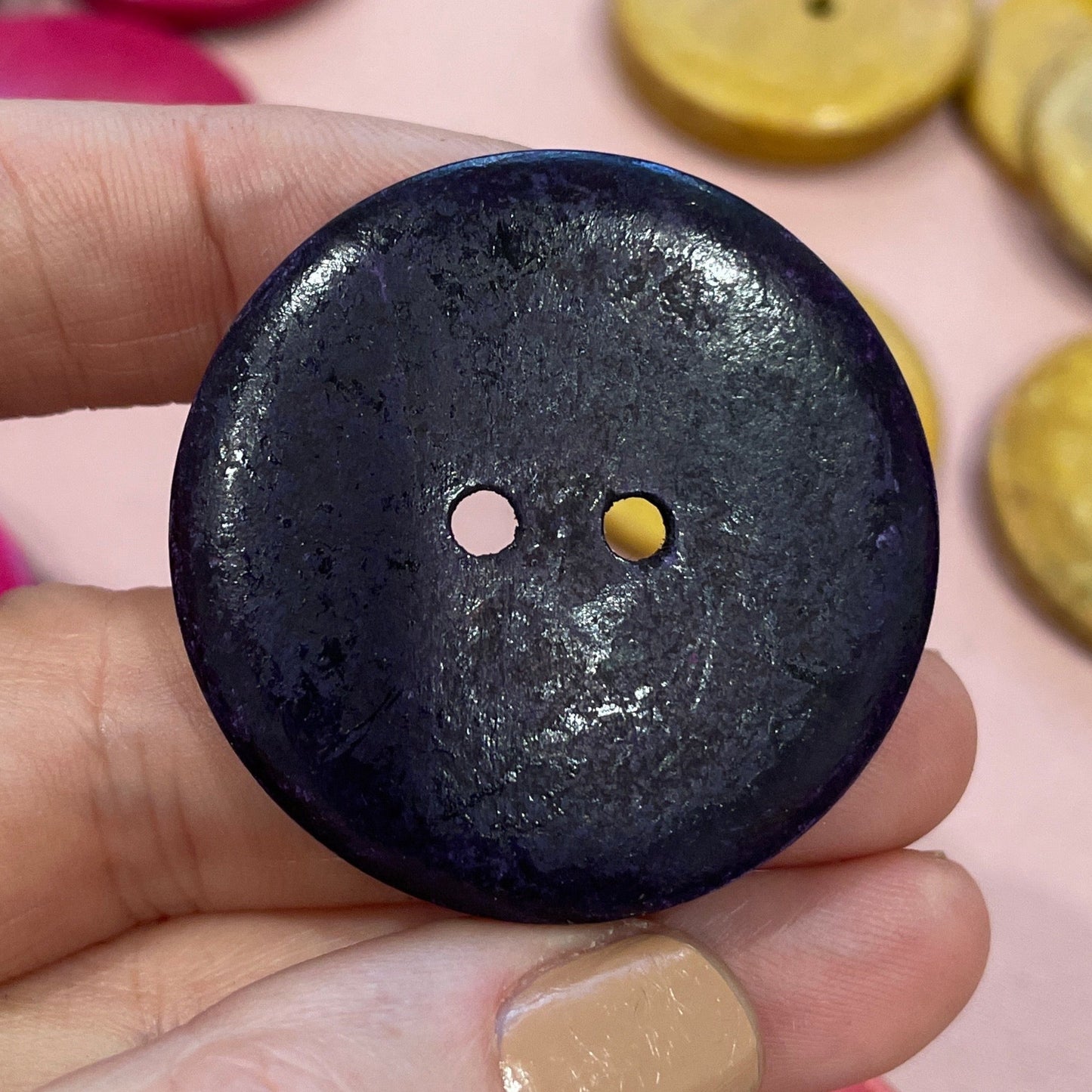 Hand holding a black button with colorful buttons in the background