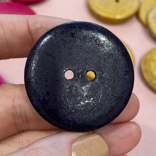 Hand holding a black button with colorful buttons in the background