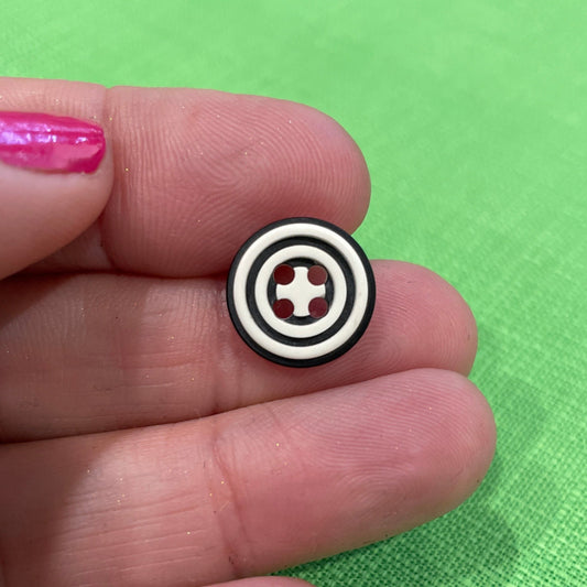 Small circular object with a cross symbol held between fingers against a green background