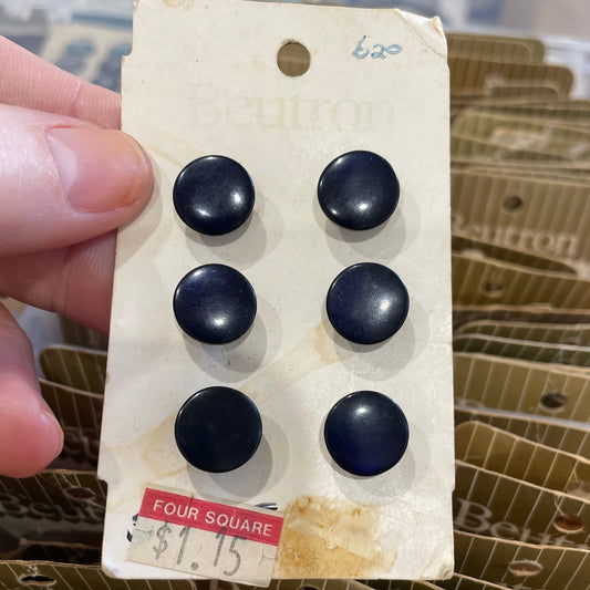 Set of black buttons on a vintage card held by a hand with a blurred background