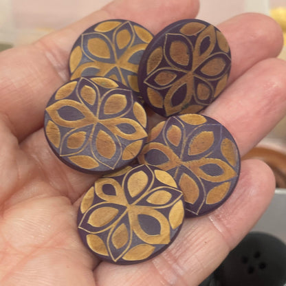 Hand holding decorative wooden buttons with a blurred background of more buttons.
