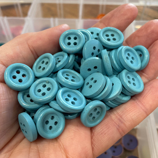 Hand holding a collection of light blue buttons with a blurred background