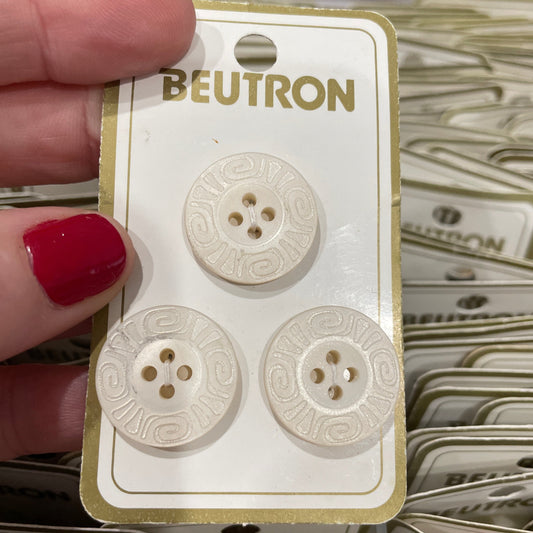 Beutron buttons on a card held by a hand with red nail polish.