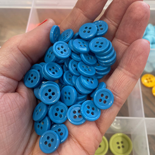 Hand holding a collection of blue buttons with a blurred background of more buttons.
