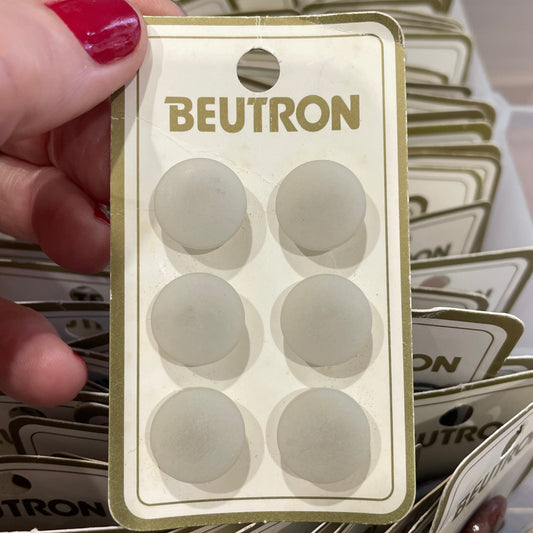 Hand holding a Beutron product packaging with multiple similar packages in the background.