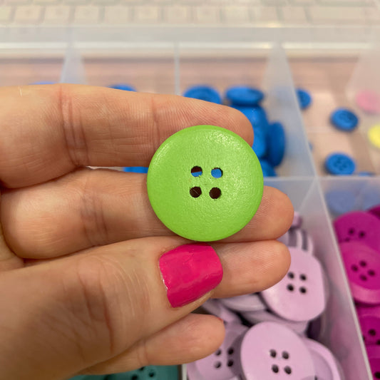 Hand holding a green button with a colorful background of buttons
