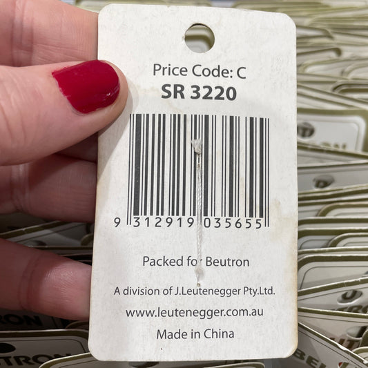Close-up of a product tag held by a hand with red nail polish, surrounded by more tags.