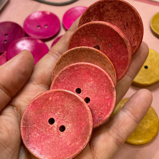 Hand holding pink buttons with a keyboard and colorful buttons in the background