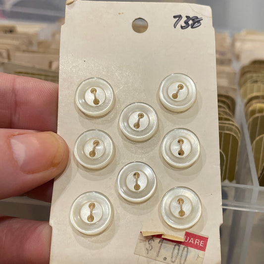Card with six white buttons held by a hand, with a blurred background