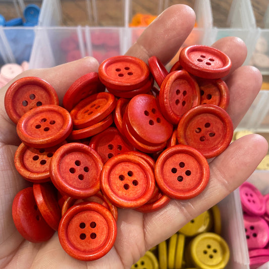 Hand holding a collection of red buttons with a blurred background of more buttons.