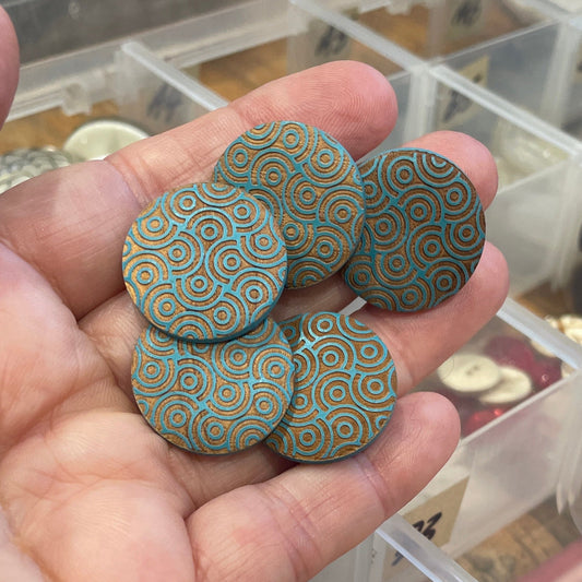 Hand holding decorative buttons with a clear container of buttons in the background