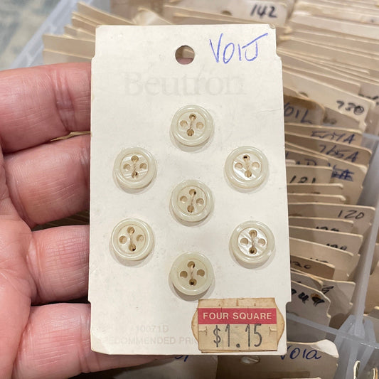 Hand holding a card with buttons in front of a collection of similar cards.