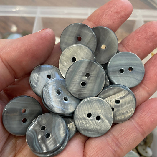 Hand holding a collection of metallic buttons with a blurred background