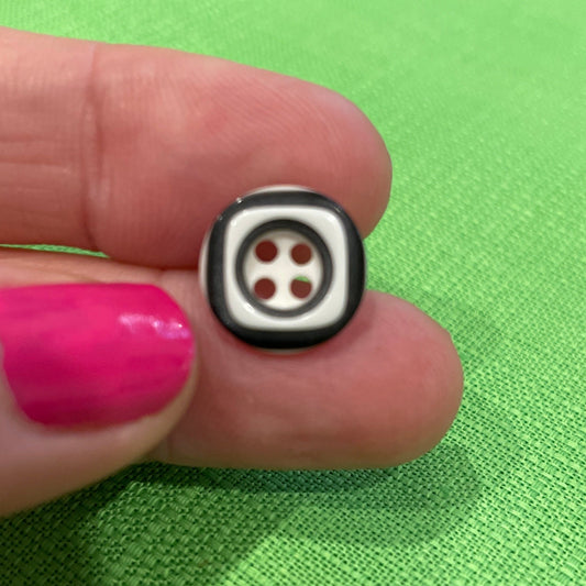 Small black and white object held between fingers against a green background