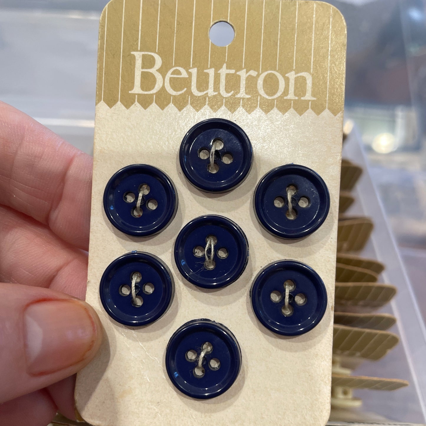 Set of blue buttons on a Beutron branded card held by a hand.