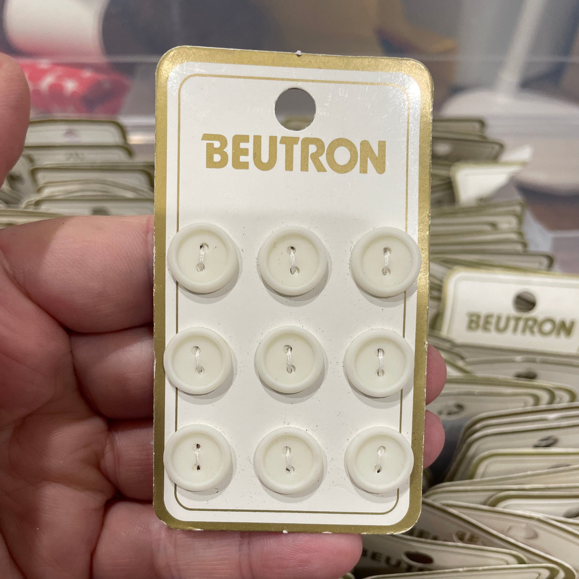 Card with white buttons held by a hand, with 'BEUTRON' branding.