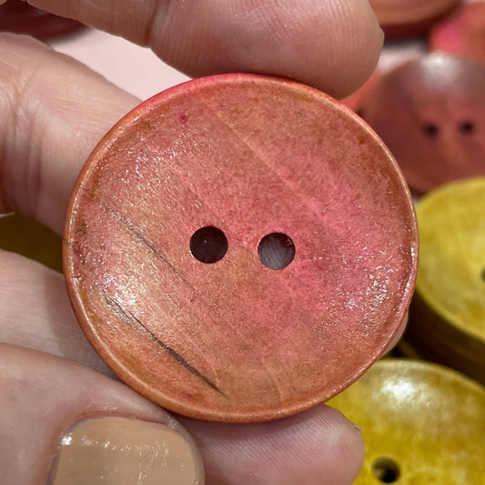Hand holding a pink button with other buttons in the background