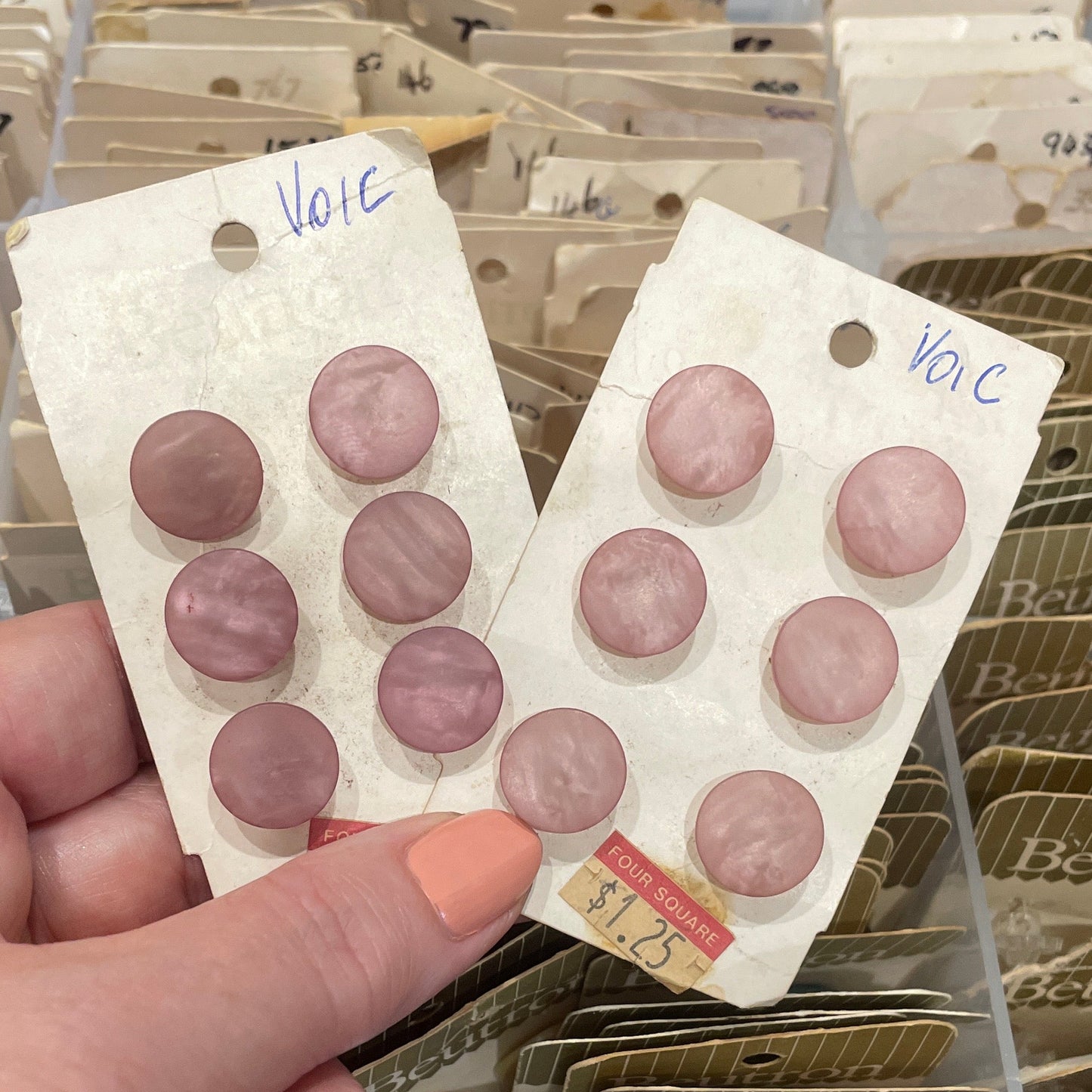 Hand holding a card with buttons, surrounded by other similar cards.