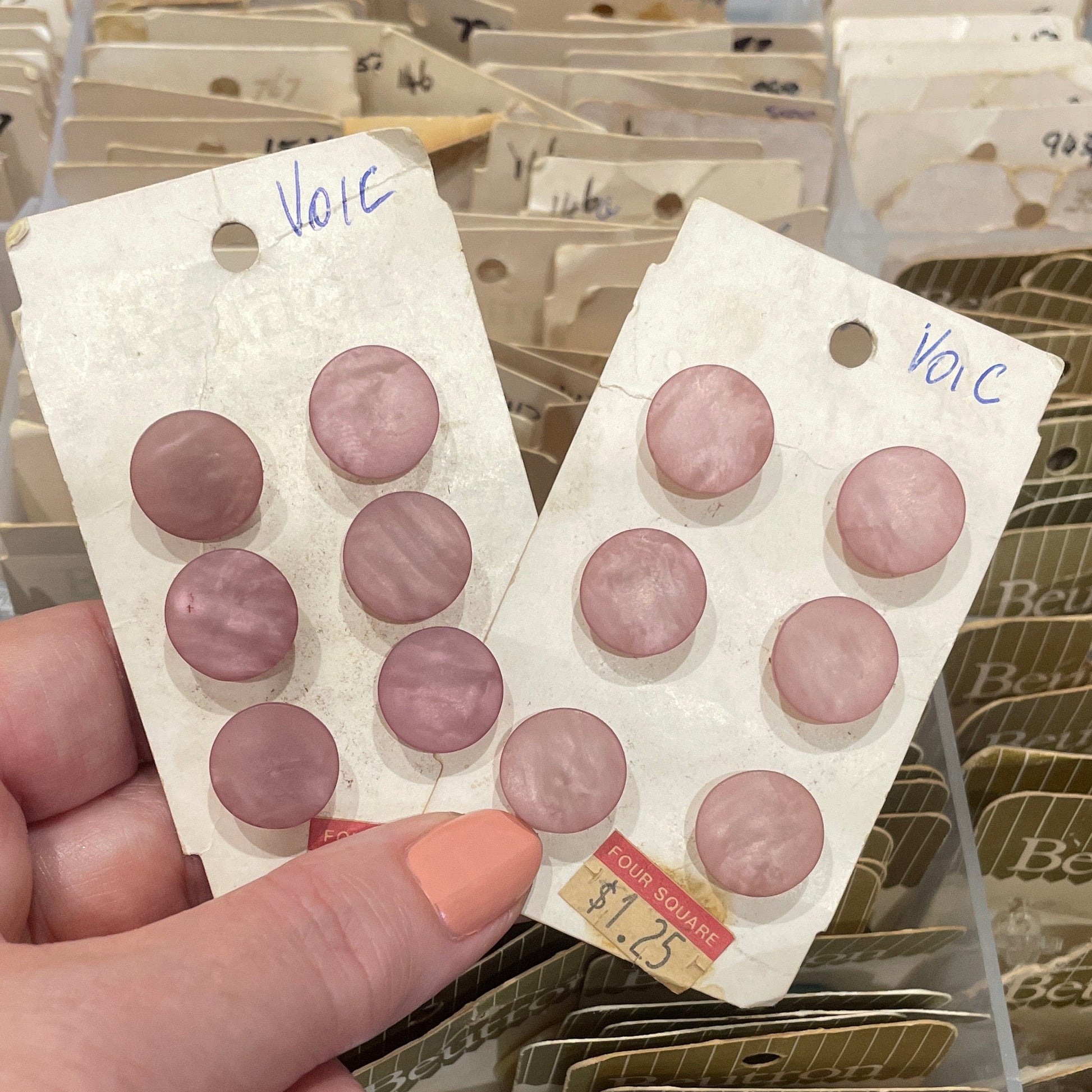 Hand holding a card with buttons, surrounded by other similar cards.
