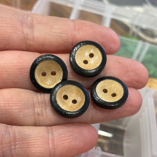 Hand holding wooden buttons with a container of colorful buttons in the background