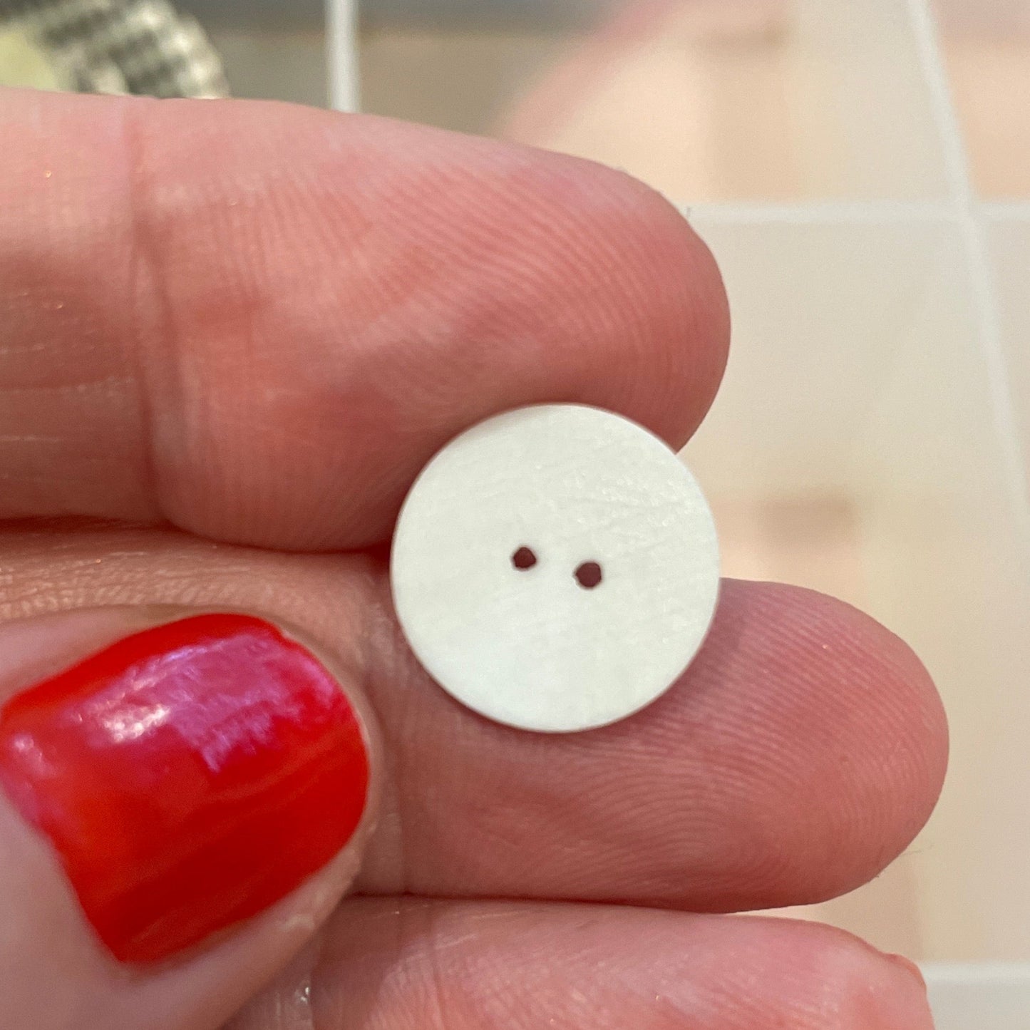 White button held between fingers with a background of various buttons