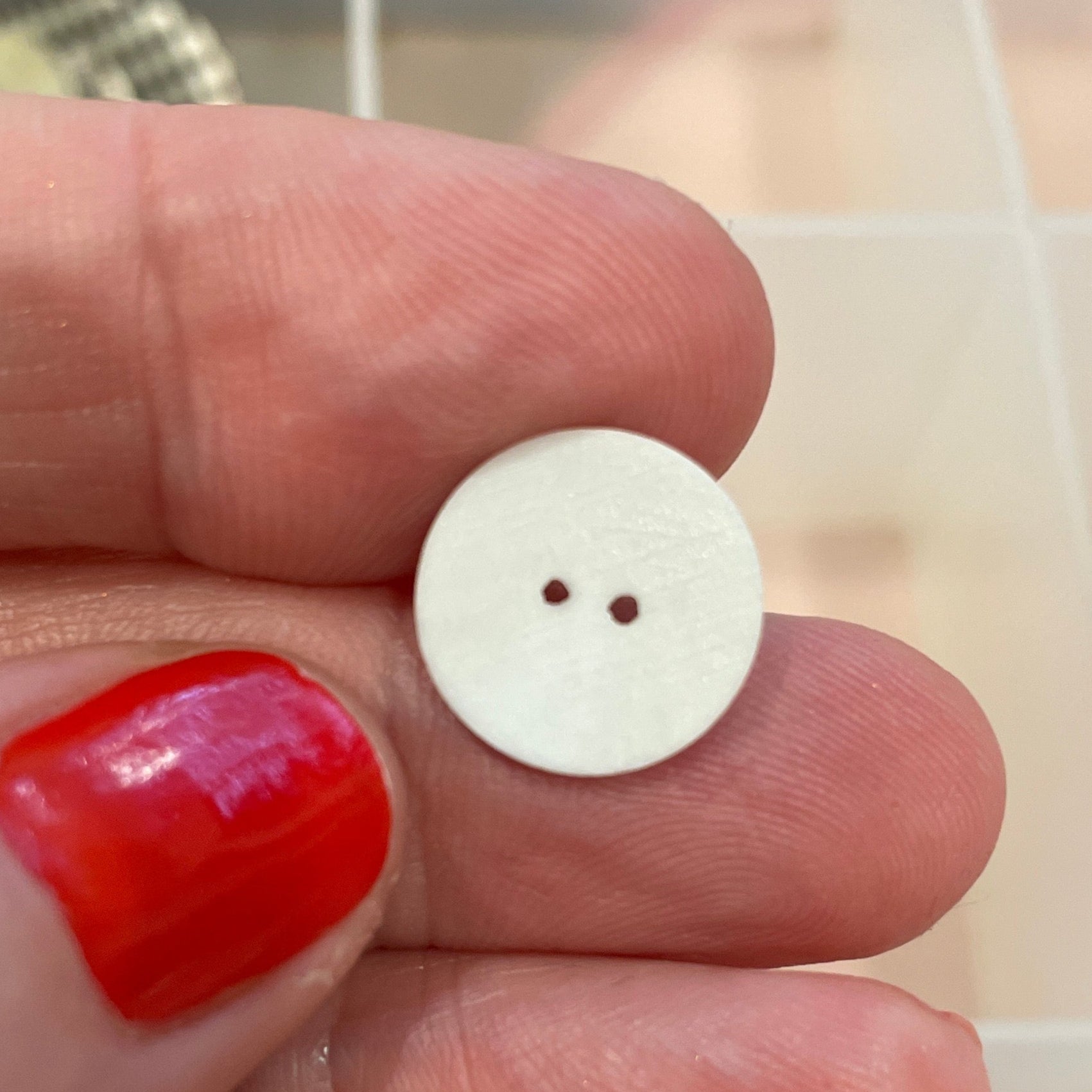 White button held between fingers with a background of various buttons