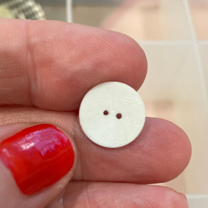 White button held between fingers with a background of various buttons