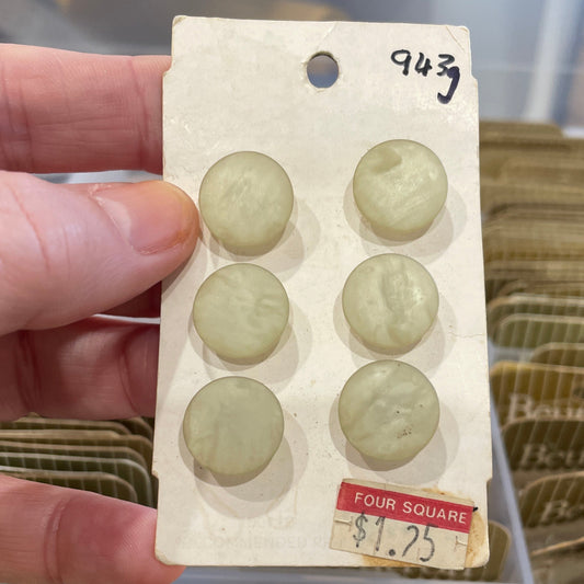Hand holding a card with six buttons and a price tag in an unclear background