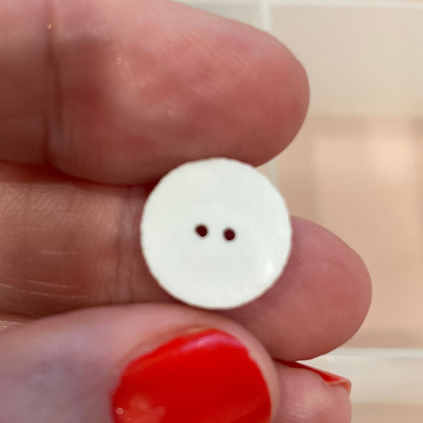 White button held between fingers with a background of various buttons