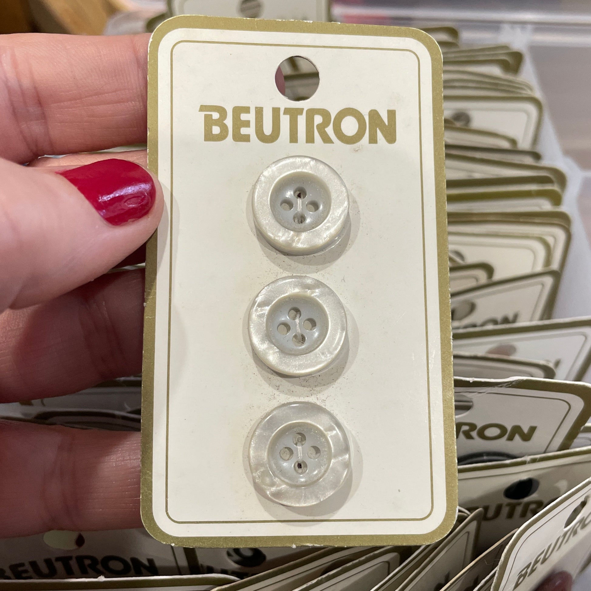 Hand holding a Beutron buttons  with more buttons in the background