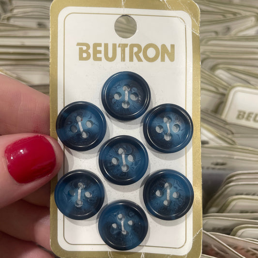 Pack of blue buttons with 'Beutron' branding held by a hand.