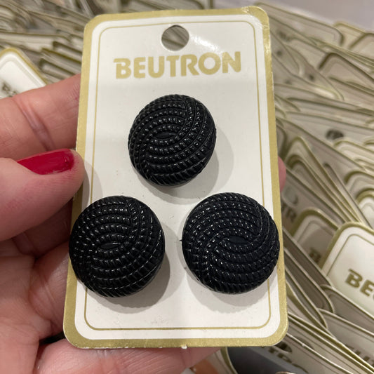 Black buttons on a BEUTRON branded card held by a hand.