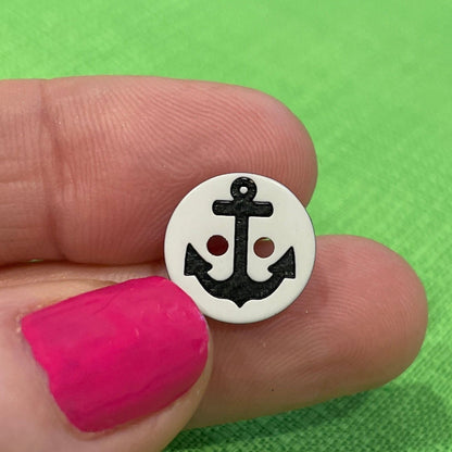 Small round object with a design held between fingers against a green background