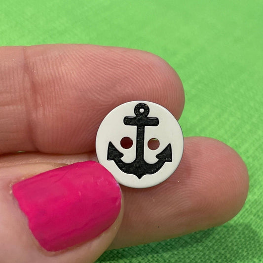 Small round object with a design held between fingers against a green background