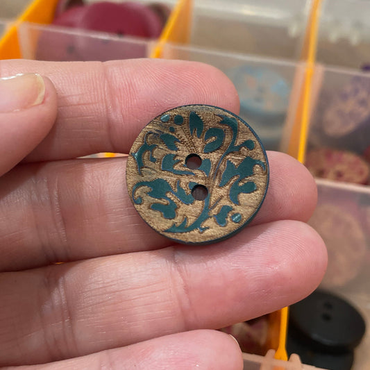 Hand holding a decorative button with a blurred background of button display