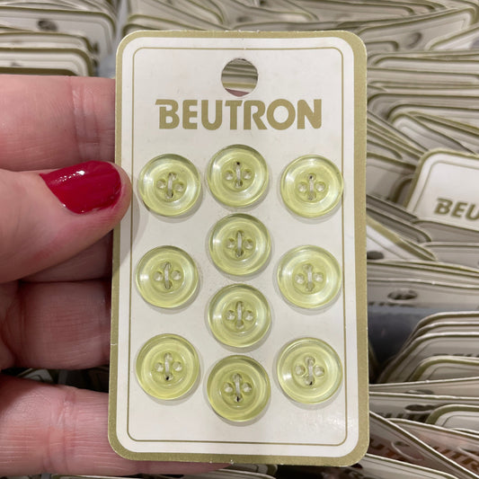 Pack of green buttons with 'Beutron' branding held by a hand.